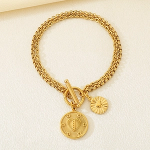 Detail of double-layer gold chain bracelet with heart charms and toggle clasp