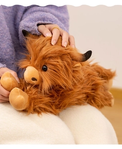 Detailed view of the soft long plush texture and cute face of the brown highland cow toy
