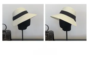 Side view detail of creamy straw sun hat with wide black ribbon on display stands