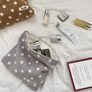 Detailed top view of polka dot corduroy cosmetic bags with skincare items on white fabric