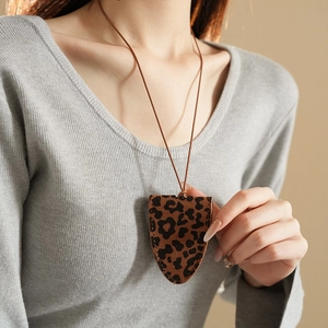 Detailed close-up of leopard print leather necklace pouch worn with gray long sleeves