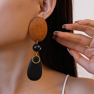 Detailed close-up of geometric wood drop earrings with brown and black oval beads