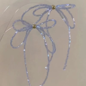 Detailed macro shot of handmade iridescent purple beaded bow studs with golden center beads