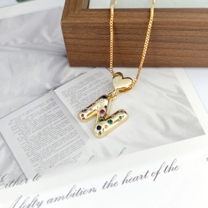 Detailed shot of gold letter N pendant with colorful zircon stones and heart-shaped clasp
