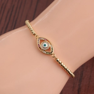 Macro view of golden Evil Eye bracelet featuring colorful zircon stones and beaded chain