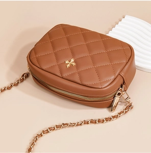 Close-up of quilted brown leather crossbody bag with golden hardware and chain strap