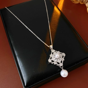 Detail of silver pearl necklace with a zircon hollow flower pendant on a black box