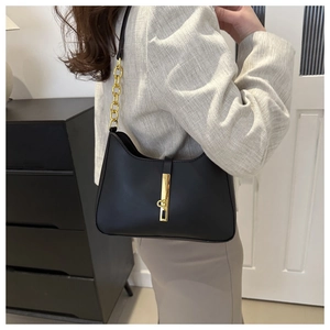 Detail of minimalist black matte leather underarm bag with thick gold chain strap