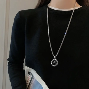 Close-up of silver compass star pendant necklace on a black sweater for men and women