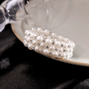 Close-up of triple-layer pearl bracelet with sparkling rhinestone spacers on white tray