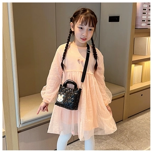 Bambina con borsa a tracolla trapuntata nera con ciondolo a coniglio e abito rosa