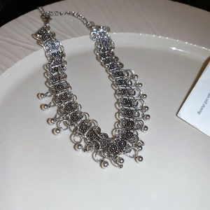 Detail of silver bohemian choker necklace with metal beads and textured rings on plate