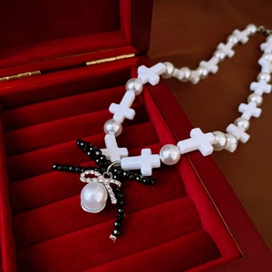 Elegant beaded necklace with white resin cross, pearl strands and diamond-set bow pendant