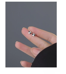 Nahaufnahme von Mini-Panda-Ohrsteckern aus S999-Silber auf einer Fingerspitze