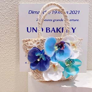 Detail of bohemian beach bag featuring blue orchid flowers and pearl bow accents