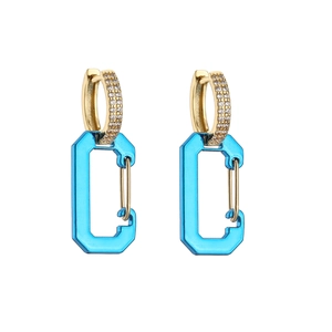 Macro detail of gold safety pin earrings with pavé crystals and translucent blue charms
