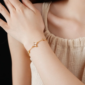 Detail of gold-plated clover bracelet with white zircon inlay on female wrist