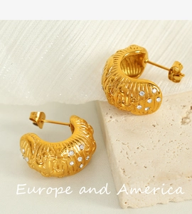Detailed view of gold C-shaped earrings with wave texture and inlaid rhinestones