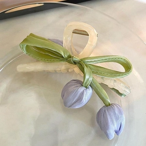 Close-up of a cream hair claw with green satin bow and lilac fabric tulip flowers