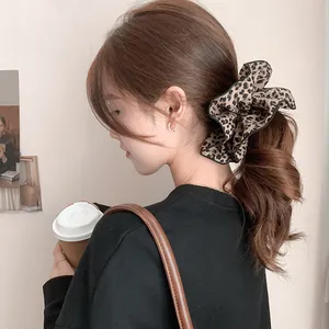 Detailed view of a double-layered leopard print scrunchie on a ponytail with gold earrings