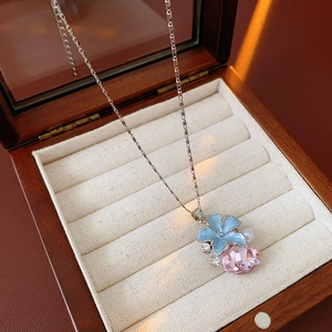 Détail du collier à fleur vintage avec pétales bleus et cristal rose dans un écrin en bois
