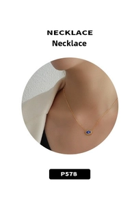 Détail d'un collier doré minimaliste avec pendentif œil bleu et rayons étoilés dorés
