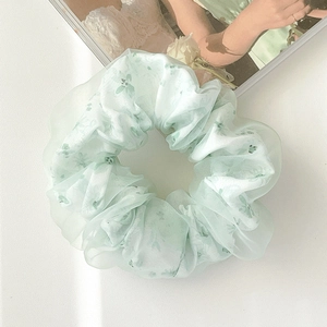 Dettaglio dell'elastico in organza verde chiaro con stampa floreale e trama velata