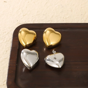 Polished 18k gold and silver heart stud earrings shown on a dark wooden display tray