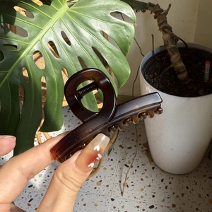 Close-up of tortoise shell pattern acrylic hair claw clip held by hand for thick hair