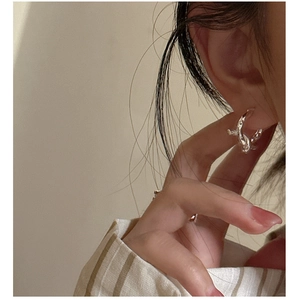 Close-up of a s925 sterling silver knotted hoop earring worn by a model in soft light