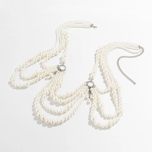 Detail of layered pearl body chain featuring silver clasps and white dangling bead strands