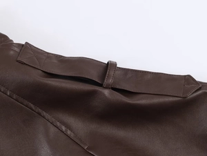 Detailed macro view of dark brown faux leather texture and stitching on the collar jacket