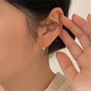 Detail of a minimalist gold hoop earring with a sparkling zircon on model's earlobe