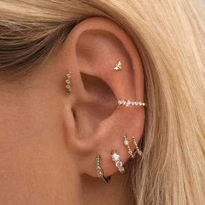 Detail of gold-plated bee stud earrings and cubic zirconia ear cuffs on ear