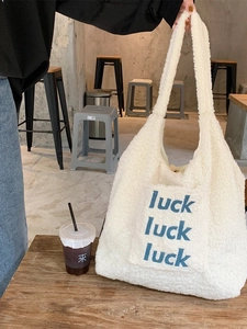 Winter plush tote bag with luck embroidery in a warm cafe scene on a wooden table