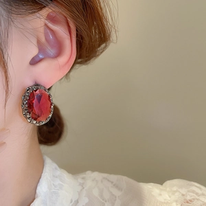 Close-up of vintage-style oval red gemstone earrings worn by model for elegant display