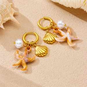 Gold plated ocean theme hoop earrings with starfish shell and pearl on sand background