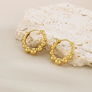 Boucles d'oreilles créoles dorées à billes sur un support en pierre blanche naturelle