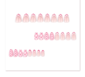 Detail of pink and white press-on nails with lace edges, red dots, and plaid patterns