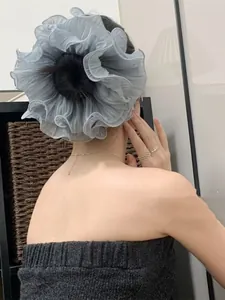 Close-up of a blue pleated oversized scrunchie styled on a bun with airy fabric texture