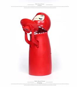 Detail of red robotic Daruma piggy bank eating coins with automatic mechanism