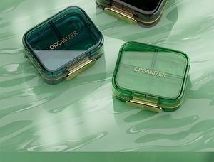 Detail of green pill organizer with metal buckle and clear multi-grid compartments