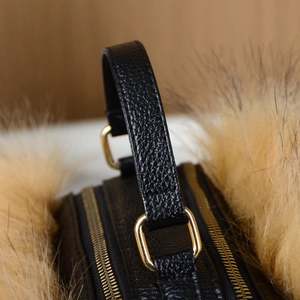 Detail of lychee pattern black leather handle with gold hardware and fur trim