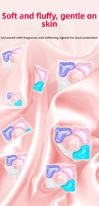 Close-up of heart-shaped multi-chamber laundry pods on elegant pink silk fabric