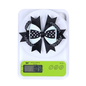 Detail showing a 10.9g layered Halloween bow clip on a white digital scale