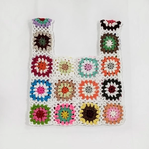 Macro view of detailed granny square crochet stitches and colorful yarn on a handmade bag