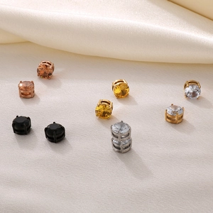Macro shot of assorted colorful zircon magnetic earrings on elegant beige silk fabric