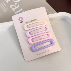 Detail of four colorful rectangular resin hair clips on a pink card in soft lighting