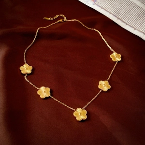 Gros plan du collier trèfle doré avec cinq motifs floraux sur fond de soie
