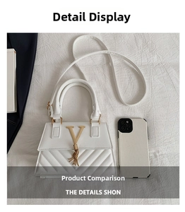Close-up of white quilted handbag with golden V-shaped metal logo and tassel details